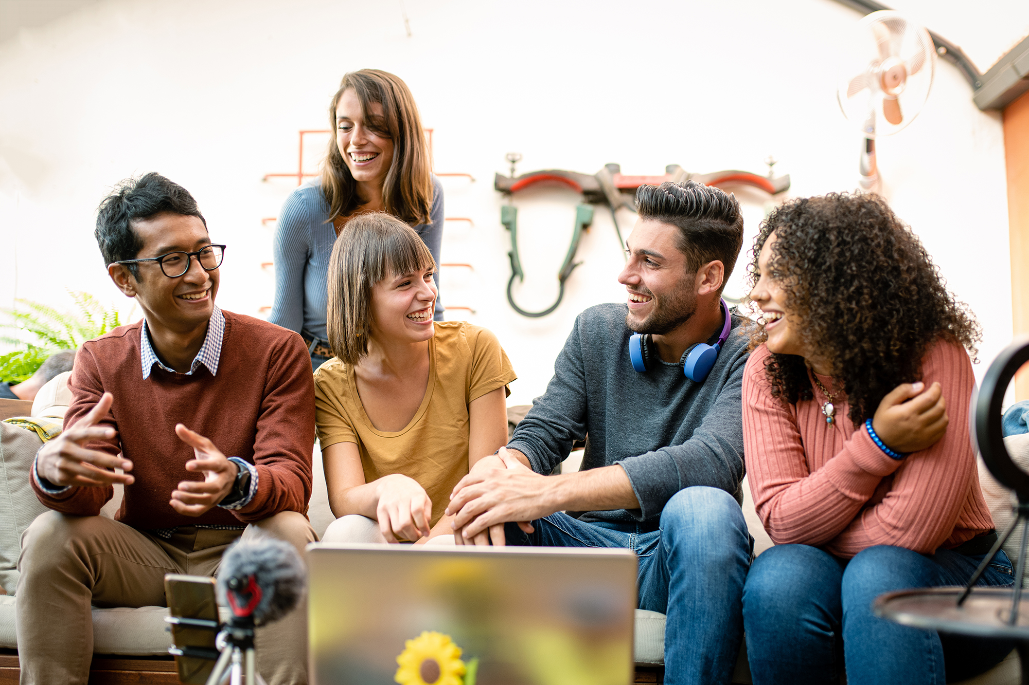 group of young millennials sharing contents and interview with webcam and laptop, influencers and vloggers having fun on live streaming, happy coworkers of a small business talking and planning