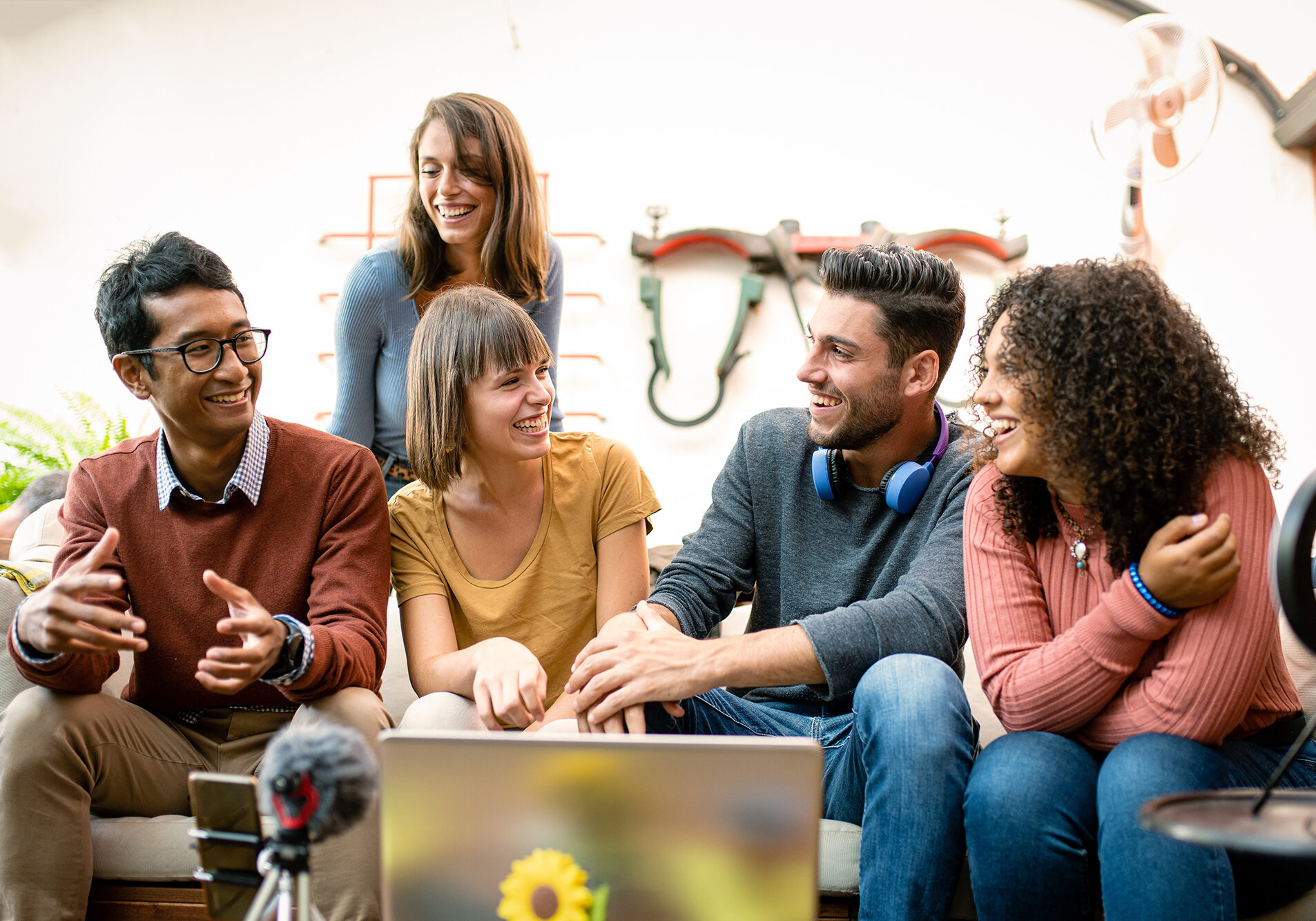 group of young millennials sharing contents and interview with webcam and laptop, influencers and vloggers having fun on live streaming, happy coworkers of a small business talking and planning